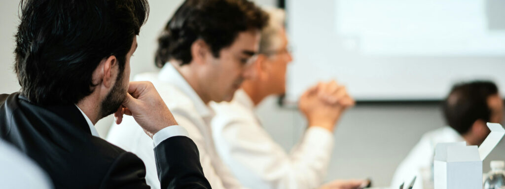 Tender Process meeting, people in suits watching a presentation