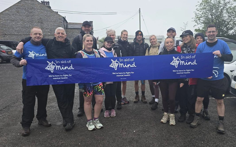 Exhausted but proud Major Recruitment team standing together holding a MIND banner after completing the Yorkshire Three Peaks Challenge, celebrating £2,720 raised for mental health charity